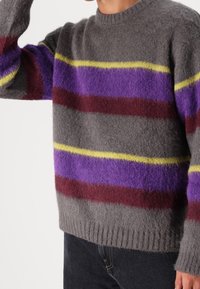 Maglione grigio in materiale soffice con ampie strisce orizzontali in viola, rosso e giallo. Polsini e orlo a costine.