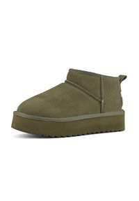 Olive green suede ankle boot with a rounded toe, minimal stitching, and flat rubber sole featuring a serrated edge.