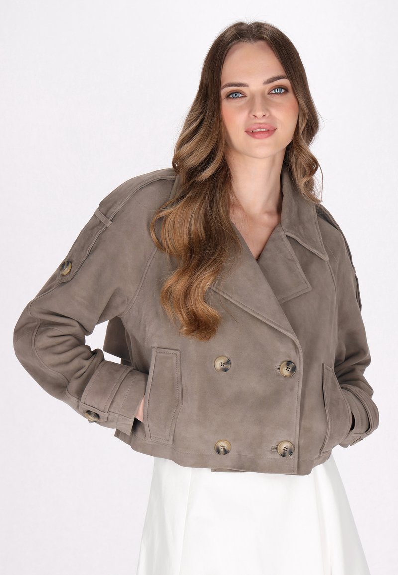 Giacca corta doppiopetto in suede taupe con grandi bottoni, colletto a punta e tasche laterali. Texture liscia con vestibilità rilassata.