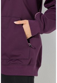 Purple hoodie featuring a front pocket with a black adjustment cord and pink accent at the cuff, made of smooth, soft fabric.