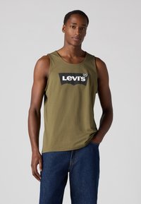 Alyvuogių spalvos be rankovių marškinėliai su juodu ir baltu Levi's logotipu, pagaminti iš medvilnės, su apvaliu kaklu ir laisvu siluetu.
