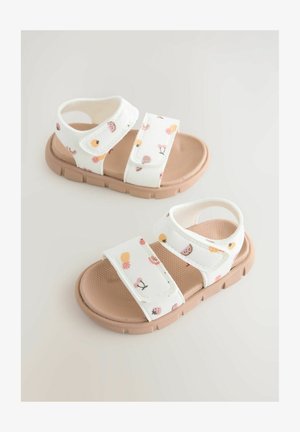 Sandali za otroke z belim tekstilnim zgornjim delom, ki ponujajo vzorec sadja in cvetja, rjav gumijast podplat, nastavljive trakove in teksturirano notranjost.