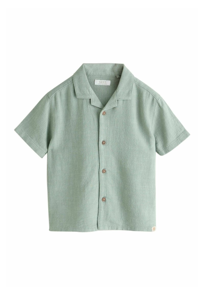 Camisa de manga corta en algodón verde claro con cierre de botones, cuello puntiagudo y tejido texturizado. Cuenta con botones marrones y una etiqueta.