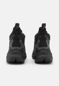 Scarpe da ginnastica nere con tomaia testurizzata, colletto imbottito e tacco prominente. Presentano accenti grigi e una suola robusta per una migliore aderenza.