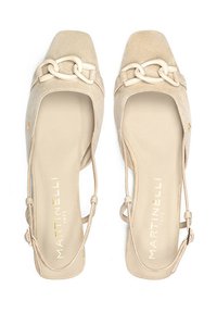 Chaussures en suède beige à bout carré avec des brides de cheville et une chaîne blanche décorative à l'avant. Semelle de couleur claire, branding minimaliste à l'intérieur.