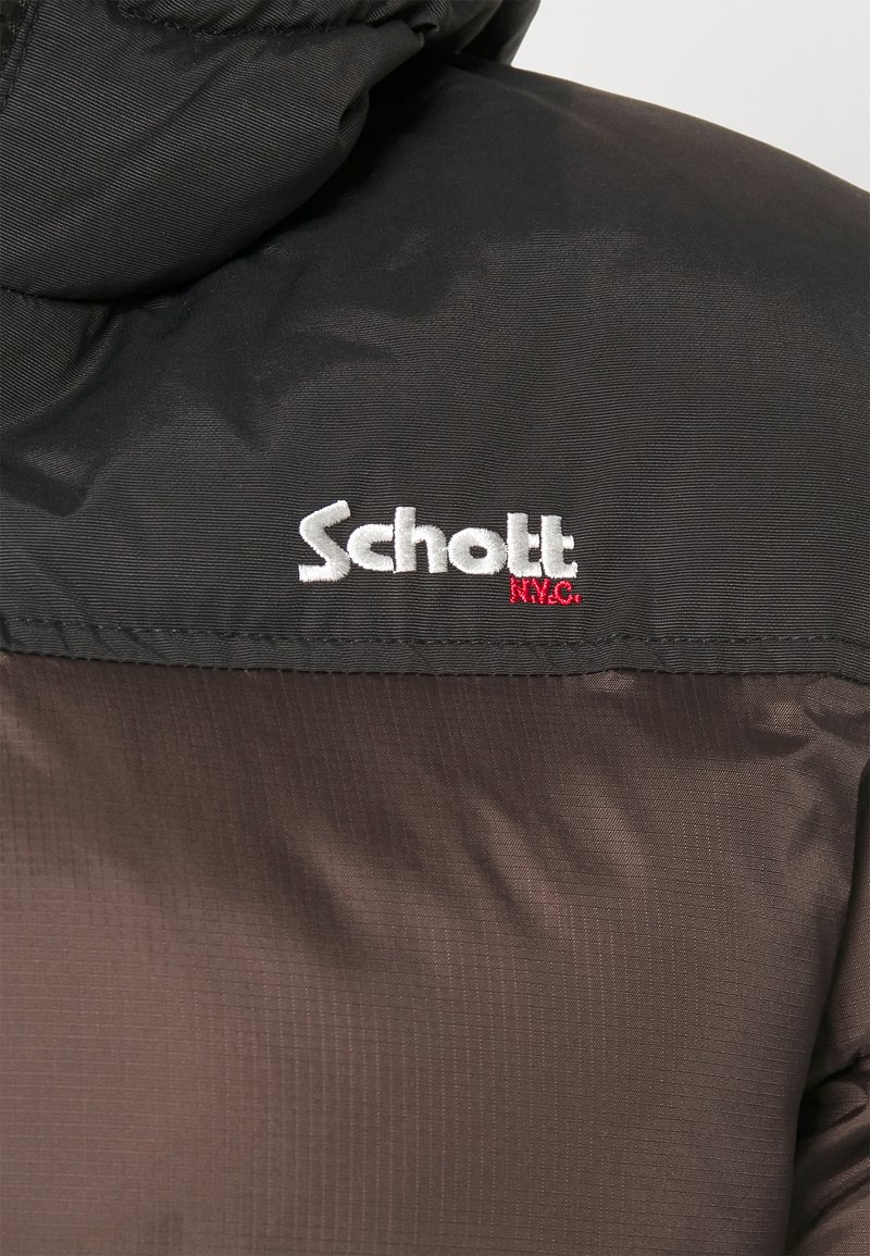 Veste rembourrée noire et marron avec une capuche. Présente une surface texturée et un logo brodé blanc en évidence, "Schott," avec des accents rouges.