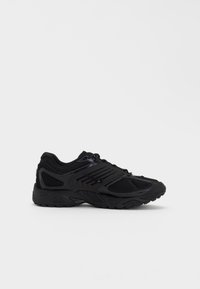Baskets de sport noires avec maille et empiècements synthétiques, semelle texturée et fermeture à lacets, vues de profil sur fond blanc.