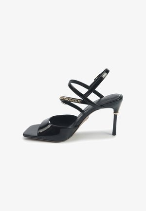Čierne lakované kožené sandále na vysokom opätku so štvorcovou špičkou, prekrývajúcimi sa popruhmi, nastaviteľným členkovým popruhom a zlatým reťazovým akcentom.