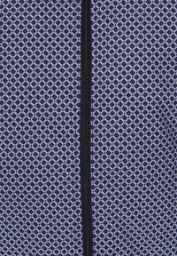 Marineblauwe stof met een patroon in een ruitjesdesign in lichtblauw. In het midden loopt een zwarte rits verticaal. Glad textuur.