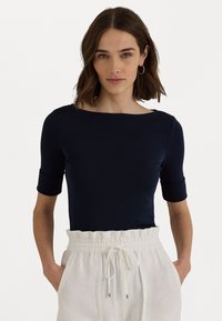 Navy blue fitted top with a boat neckline and short sleeves, made of a smooth fabric. Paired with light, drawstring waist linen trousers.
