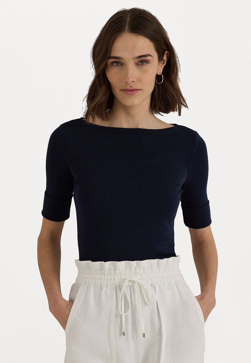 Navy blue fitted top with a boat neckline and short sleeves, made of a smooth fabric. Paired with light, drawstring waist linen trousers.
