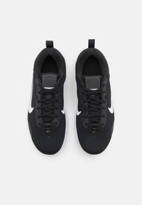 Scarpe da ginnastica nere con tomaia in tessuto texturizzato, dettagli bianchi e lacci neri. Presentano un colletto imbottito e una suola in gomma bianca.