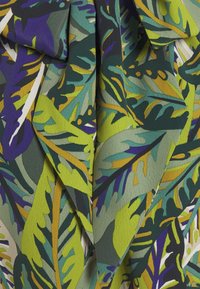 Tissu texturé avec un motif de feuilles vertes, violettes et marron. Comprend des feuilles qui se chevauchent et des couleurs contrastées qui rehaussent le design.