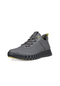 Szare buty sportowe z teksturowaną cholewką, żółtymi akcentami, elastycznymi sznurówkami oraz elastyczną, żłobioną podeszwą dla lepszej przyczepności.