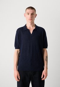 Marineblå kortermet polo skjorte laget av lett strikket stoff, med klassisk krage, ribbestrikket kant og subtil tekstur.