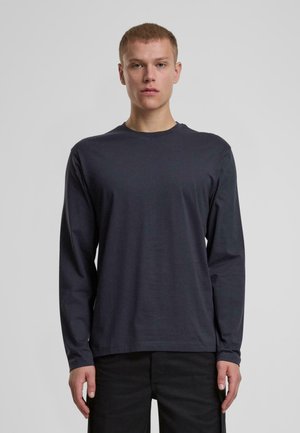 T-shirt a maniche lunghe, di colore grigio scuro, realizzato in cotone liscio, con scollatura a girocollo e orlo dritto, indossato con pantaloni neri. Nessun motivo o accento visibile.