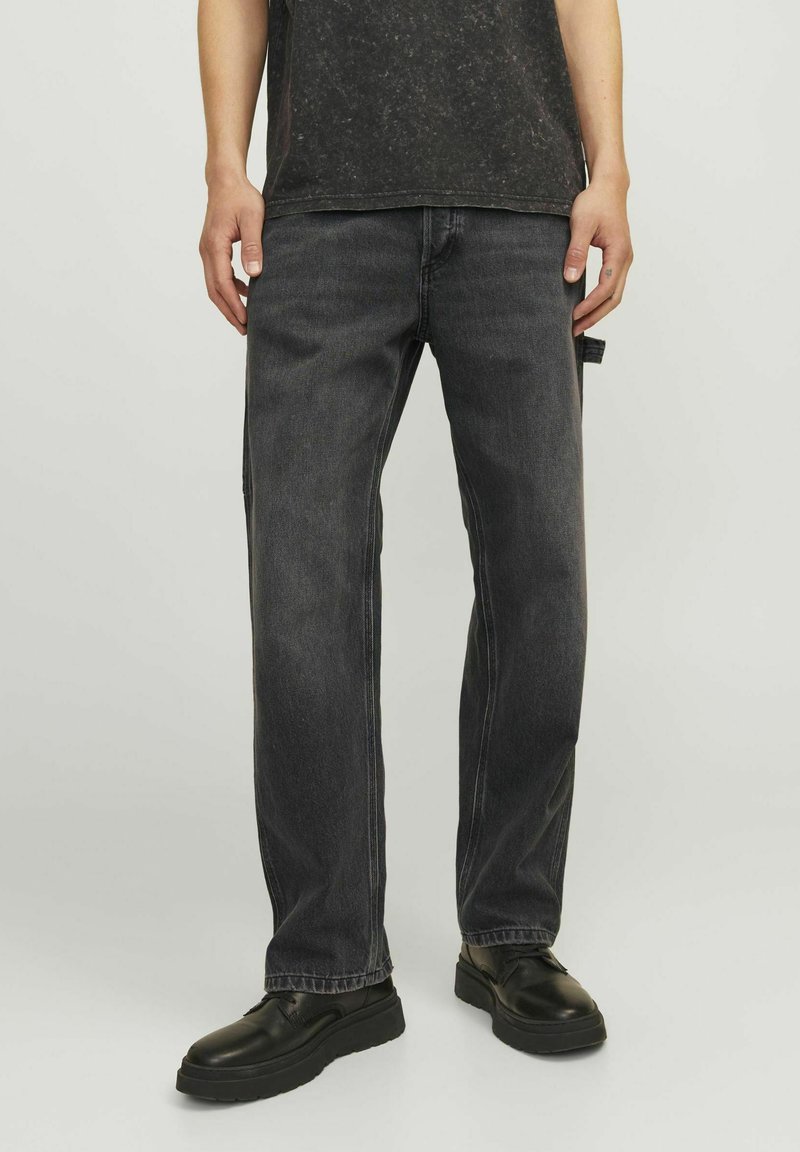 Svarta jeans med rak bendesign, med subtila bleknings- och sömnadsdetaljer. Kombinerat med svarta skor för en komplett look.
