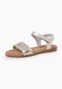 Metallic silver sandals with a woven strap design, adjustable ankle strap, and a cushioned insole, set on a flat tan sole.