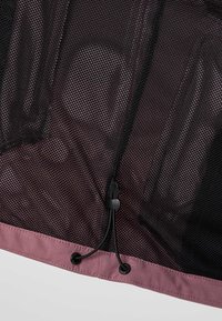 Tissu en maille noire avec un ourlet rose et un cordon réglable pour resserrer ou fixer le matériau.