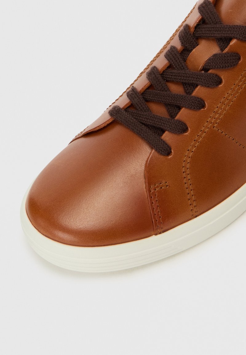 Braune Ledersneaker mit glatter Oberfläche, dunkelbraunen Schnürsenkeln und weißer Sohle. Mit einer Steppnaht entlang der Kanten.