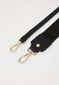 Schwarzer verstellbarer Riemen mit goldfarbigen Metallclips und einem Lederaufsatz. Verfügt über eine glatte Textur und ein robustes Design für Langlebigkeit.