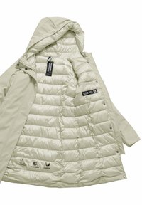 Parka beige chiaro con cappuccio, caratterizzata da un interno trapuntato, chiusure a scatto e etichette che evidenziano la resistenza all'acqua e il materiale di imbottitura.