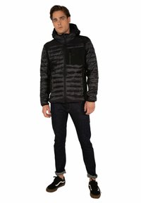 Giacca nera isolata con zip frontale, cappuccio e tasca sul petto; presenta cuciture orizzontali e una texture del tessuto liscia.