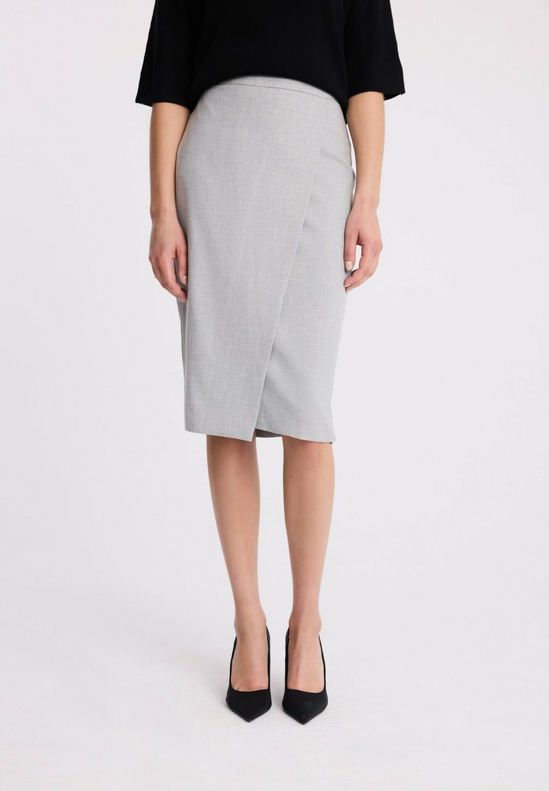 Szara spódnica o kroju kopertowym, z gładką teksturą i długości do kolan, w komplecie z czarnymi szpilkami w szpic.