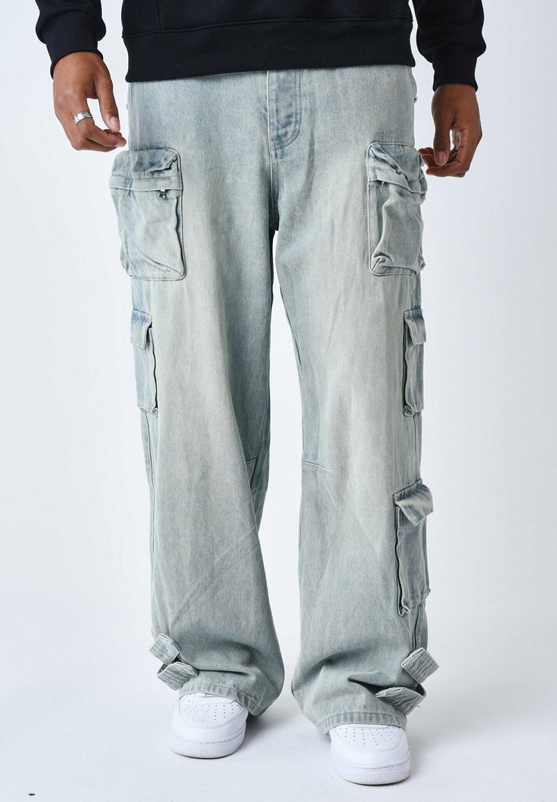 Pantalons cargo bleu clair avec de multiples poches à rabat, coupe ample et poignets ajustables. Fabriqués en denim avec une texture décolorée et usée.