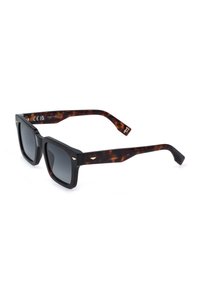 Lunettes de soleil carrées noires avec verres foncés et branches en écaille de tortue comportant de petits accents argentés et des marques de la marque.