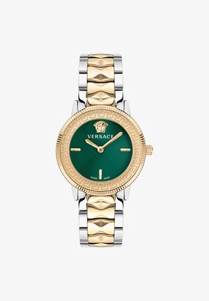 Versace kell, millel on kuldse tooni raami, roheline kellasefär ja hõbedasest lingibraatia. Märkimisväärsed detailid hõlmavad lõvi embleemi ja Kreeka võtmemustrit.