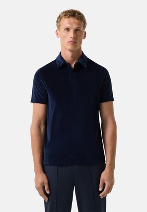 Polo en velours bleu marine avec un col classique, des manches courtes et une coupe légèrement ajustée. Texture lisse sans motifs visibles.