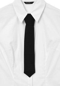Camicia bianca con colletto a punta e una cravatta nera legata in modo ordinato, centrata sotto il colletto.