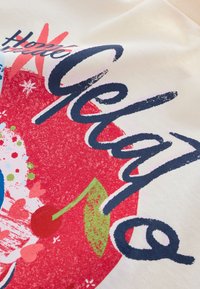 Pamut szövet, színes mintázattal, piros, kék és zöld elemekkel. A szöveg "Hello Gelato" vastag tengerészkék betűkkel, grafikus díszítésekkel.