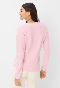Helles rosa Strickpullover mit lockerer Passform, langen Ärmeln und geripptem Design, ausgestattet mit einem runden Halsausschnitt und subtilen Nähten.