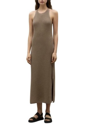 Vestido largo beige con canalé y sin mangas, con una abertura lateral. Presenta una silueta ajustada y una textura lisa, combinado con sandalias planas negras.