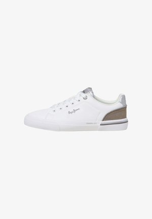 Witte lage sneaker met veters, beige suède hielstuk, zilveren logo aan de zijkant en grijze accenten op de tong en zool, zijaanzicht.