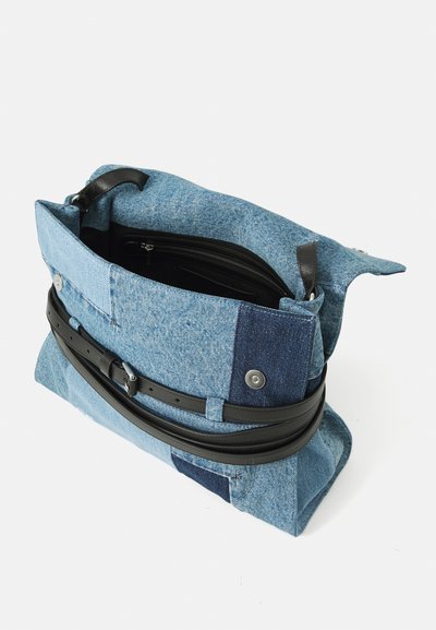 Rectangularna torba od patchwork trapera s crnim kožnim remenom, otvorenog vrha koji otkriva unutrašnji džep na zatvarač i kopču na dugme sa strane.