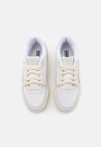 Zapatillas blancas con parte superior de cuero, caja de los dedos texturizada y cordones redondos. Presentan acentos en beige claro en la suela y la lengua.