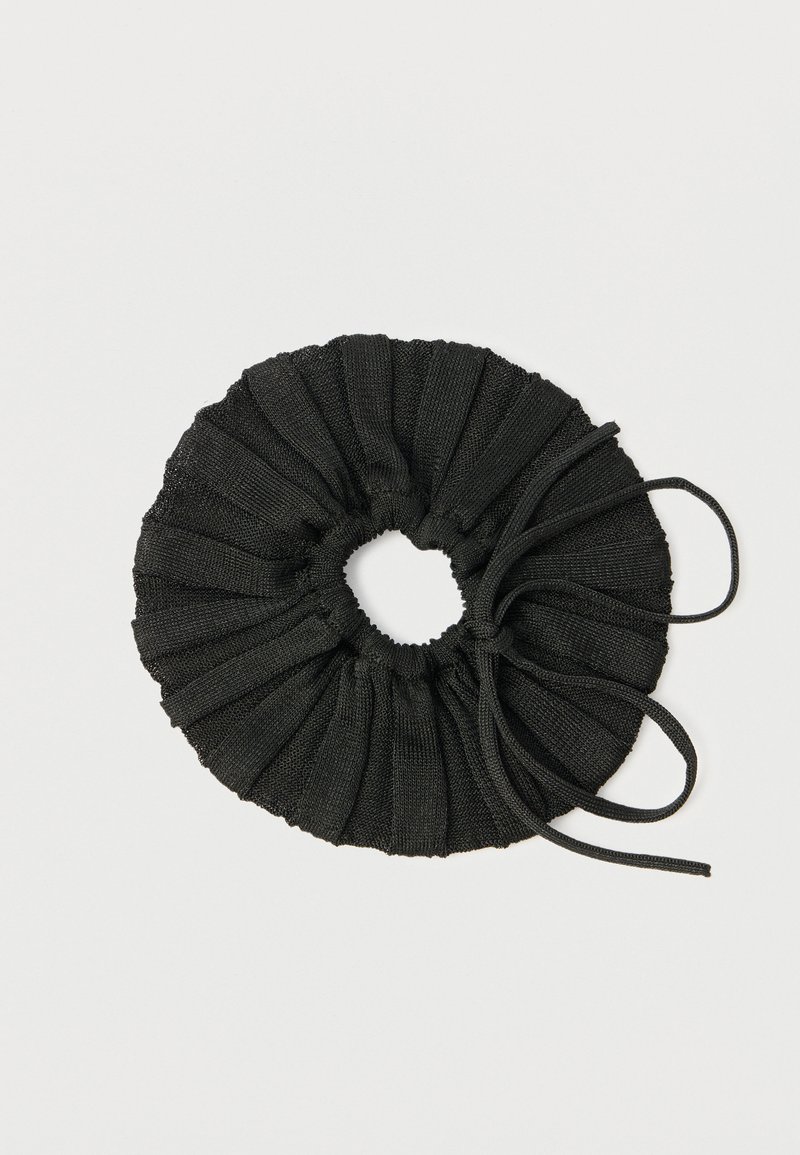Scrunchie in tessuto nero con texture plissettata e apertura centrale. Presenta due lacci sottili per la chiusura. Design semplice e circolare.