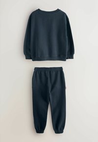 Sudadera de un azul marino oscuro con cuello redondo y puños acanalados, combinada con pantalones de chándal ajustados que tienen una cintura elástica.