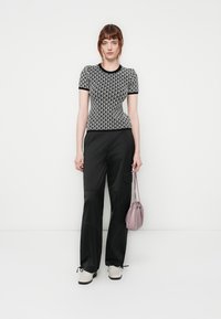 Zwart-wit gestreepte fitted top met korte mouwen, gecombineerd met losse zwarte broeken. Een lichtroze handtas en witte schoenen maken de look af.