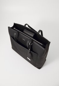 Svart lær tote bag med preget mønster, glidelås-lukking, to hender, utvendig lomme og bagasjetaggholder.