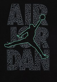 Camiseta negra con el texto "AIR JORDAN" en gris texturizado y una silueta verde neón de una figura saltando que sostiene un balón de baloncesto.
