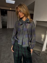 Plaid blouse in dark blue and green, features a large bow at the collar. Paired with wide-leg plaid trousers in black and green.