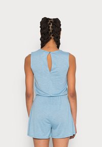 Jumpsuit sin mangas de color azul claro con detalle de corte en la espalda, cinturilla elástica y piernas cortas. Hecho de una tela suave y texturizada.