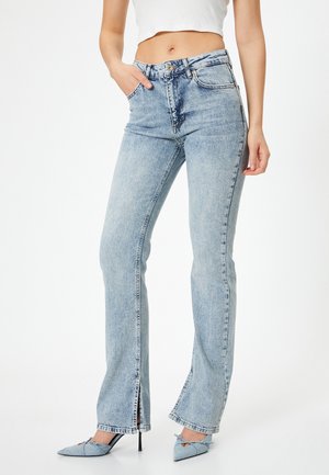 Hellblaue, ausgestellte Jeans mit hoher Taille, Fronttaschen und seitlichen Schlitzen am Saum. Glatte Textur, lässiges Design.