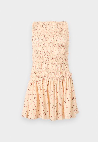 Εκρού φόρεμα χωρίς τιράντες με σφηκοφωλιά κορσέ και βολάν στην φούστα, με διάσπαρτες μικρές κόκκινες πουά σε όλο το ύφασμα.