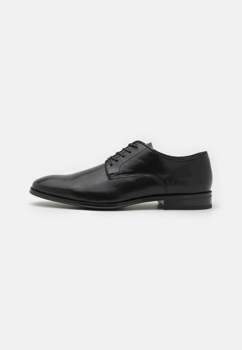 Sapato de couro preto com um acabamento liso, bico arredondado, design de atacador com seis ilhós e um salto baixo e empilhado.