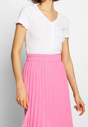 Hvid ribbet top med korte flæseærmer og V-hals, kombineret med en pink plisseret nederdel med elastiksyning i taljen.